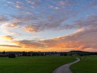 Keilförmige Wolkenschicht über Höhenberg leuchtet im Abendlicht orange